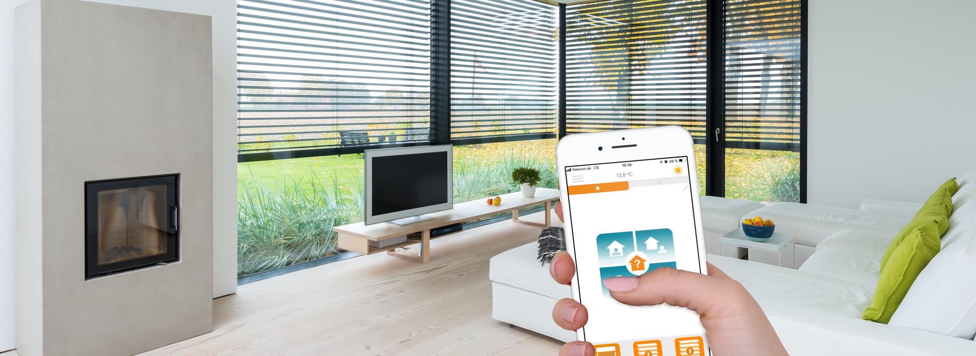 Hand mit Smartphone (Smart Home App) Hintergrund Fensterfront im Wohnzimmer