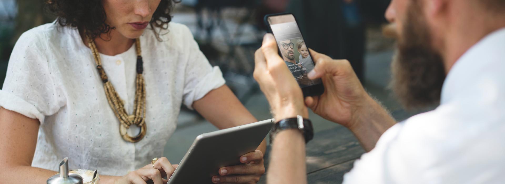 Frau und Mann im Anschnitt im Cafe mit mobilen Endgeräten