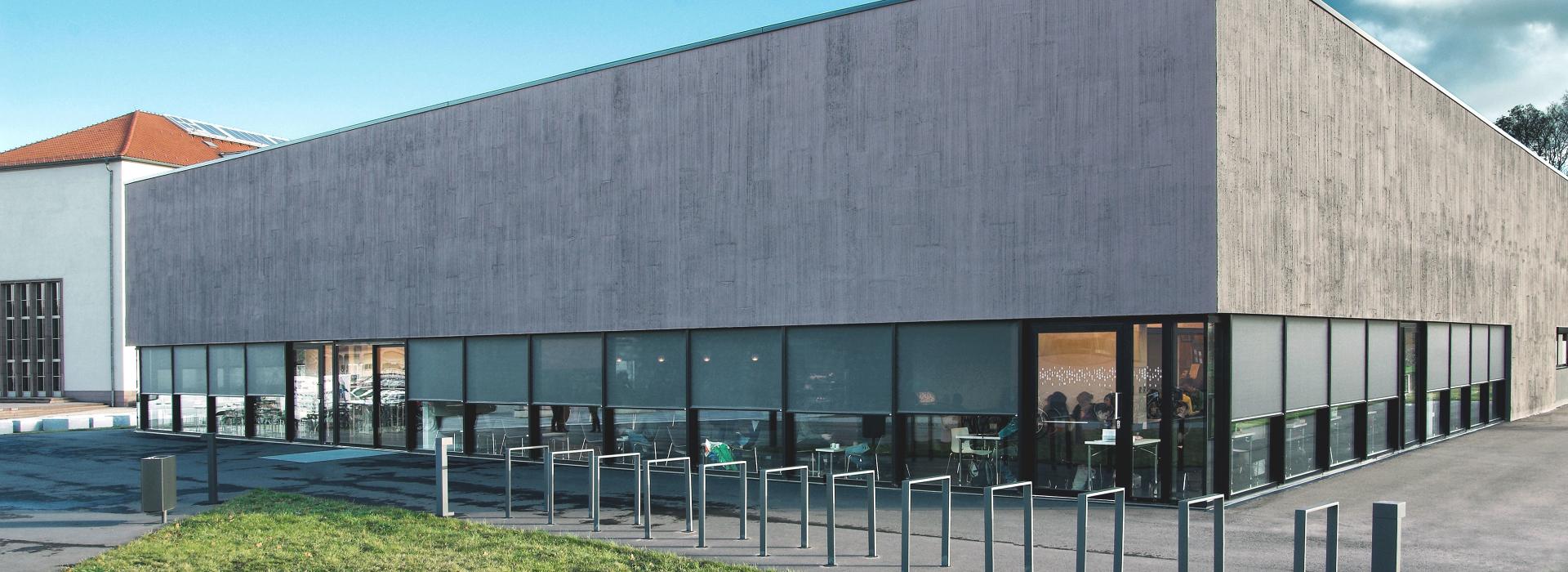 Moderner, zweigeschossiger Baukörper mit umlaufender Fensterfront und Vorbautextilscreens