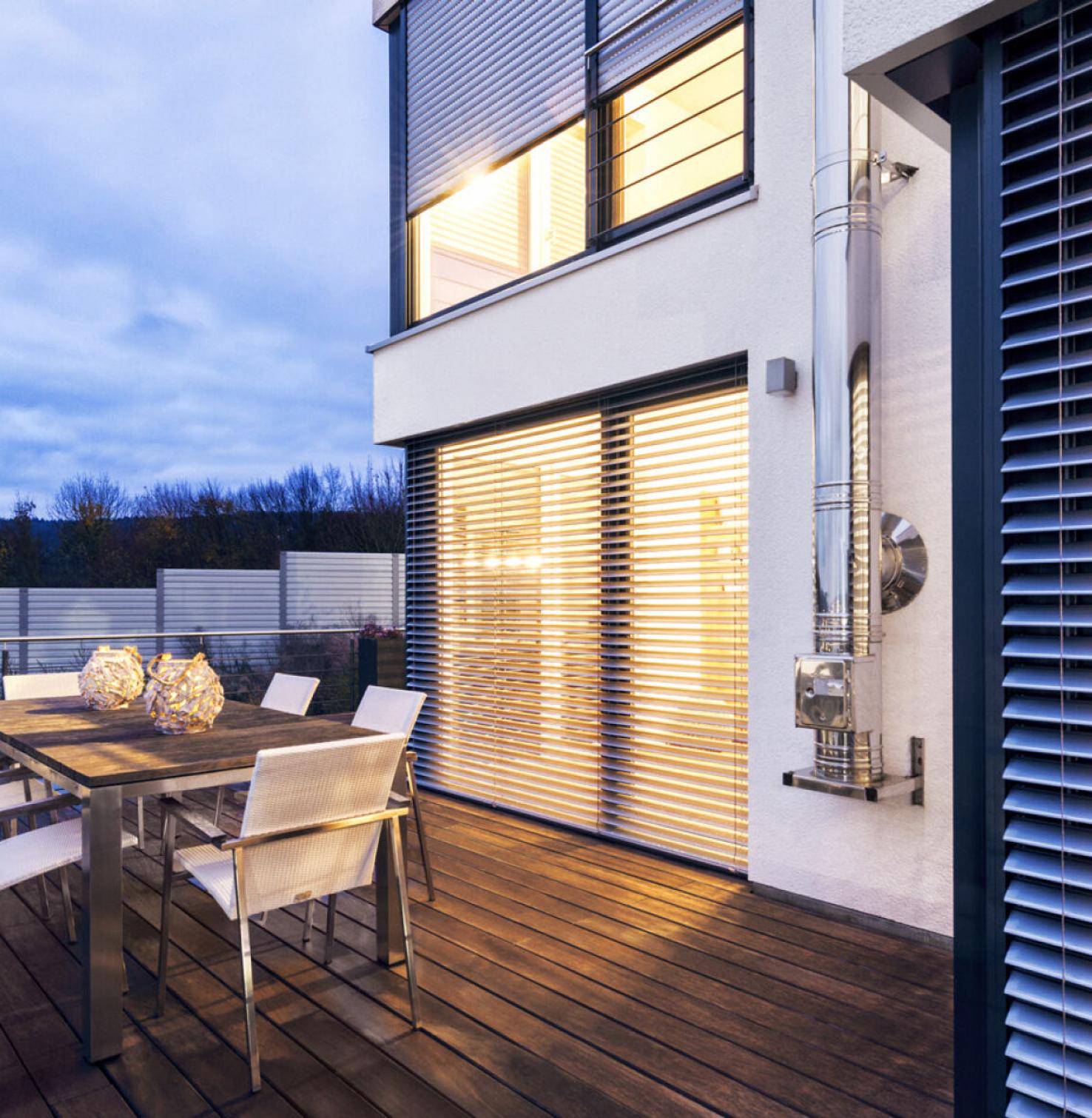 Haus mit Terrasse am Abend mit Aufsatzraffstoren innen hell beleuchtet