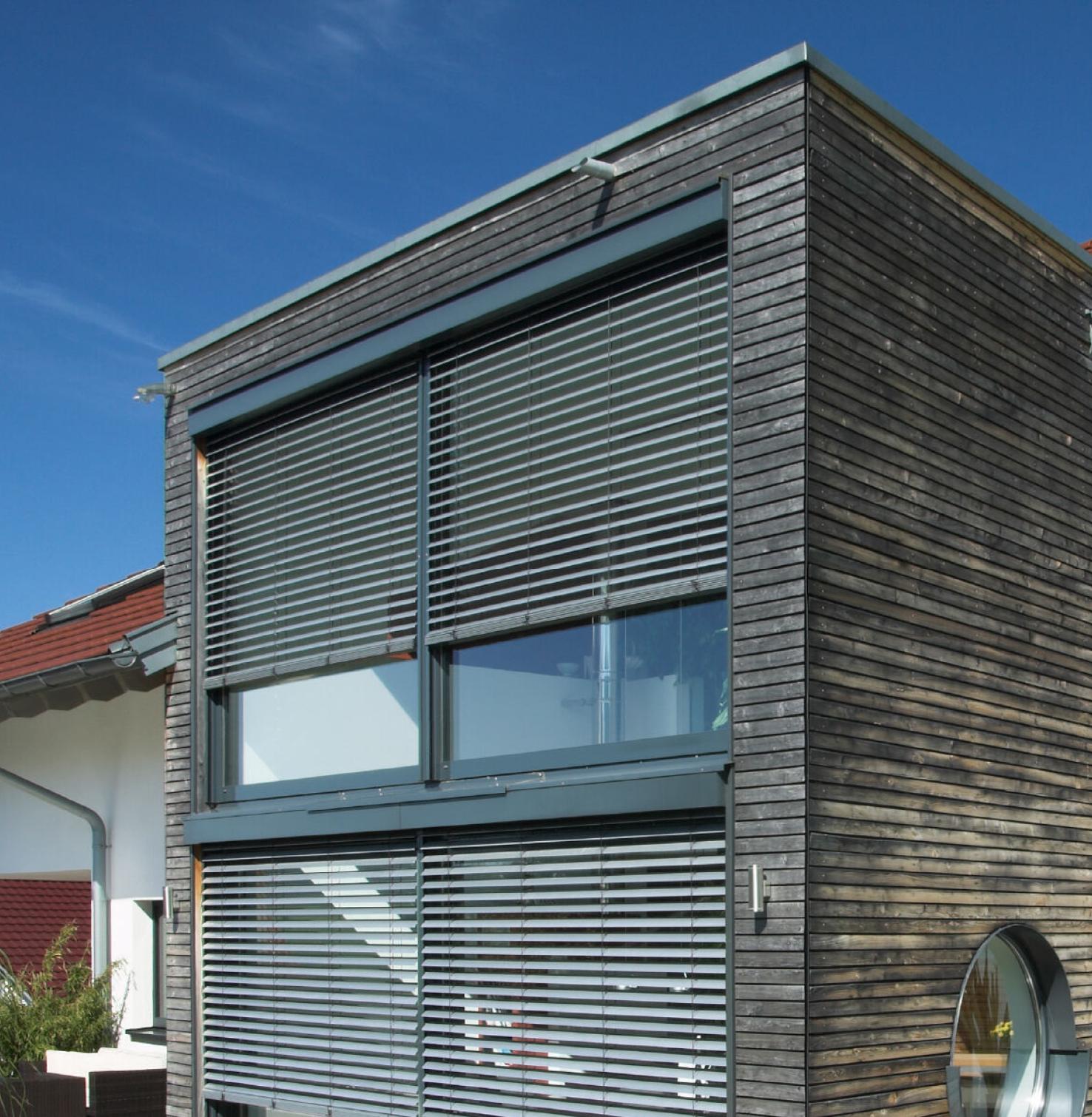 Haus mit Holzfassade und Vorbauraffstoren von ROMA