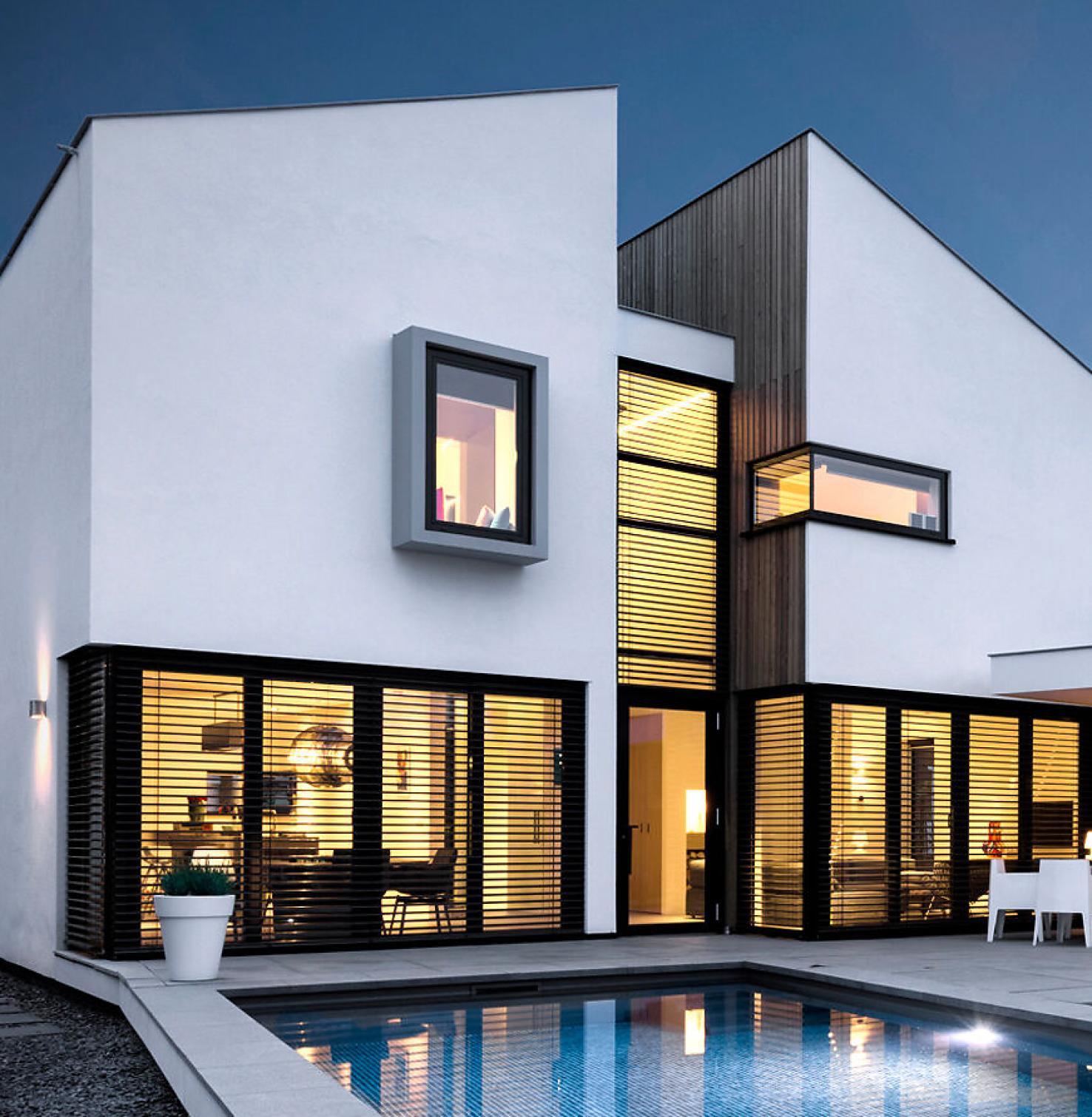 Haus mit Pool und Raffstoren innen hell beleuchtet