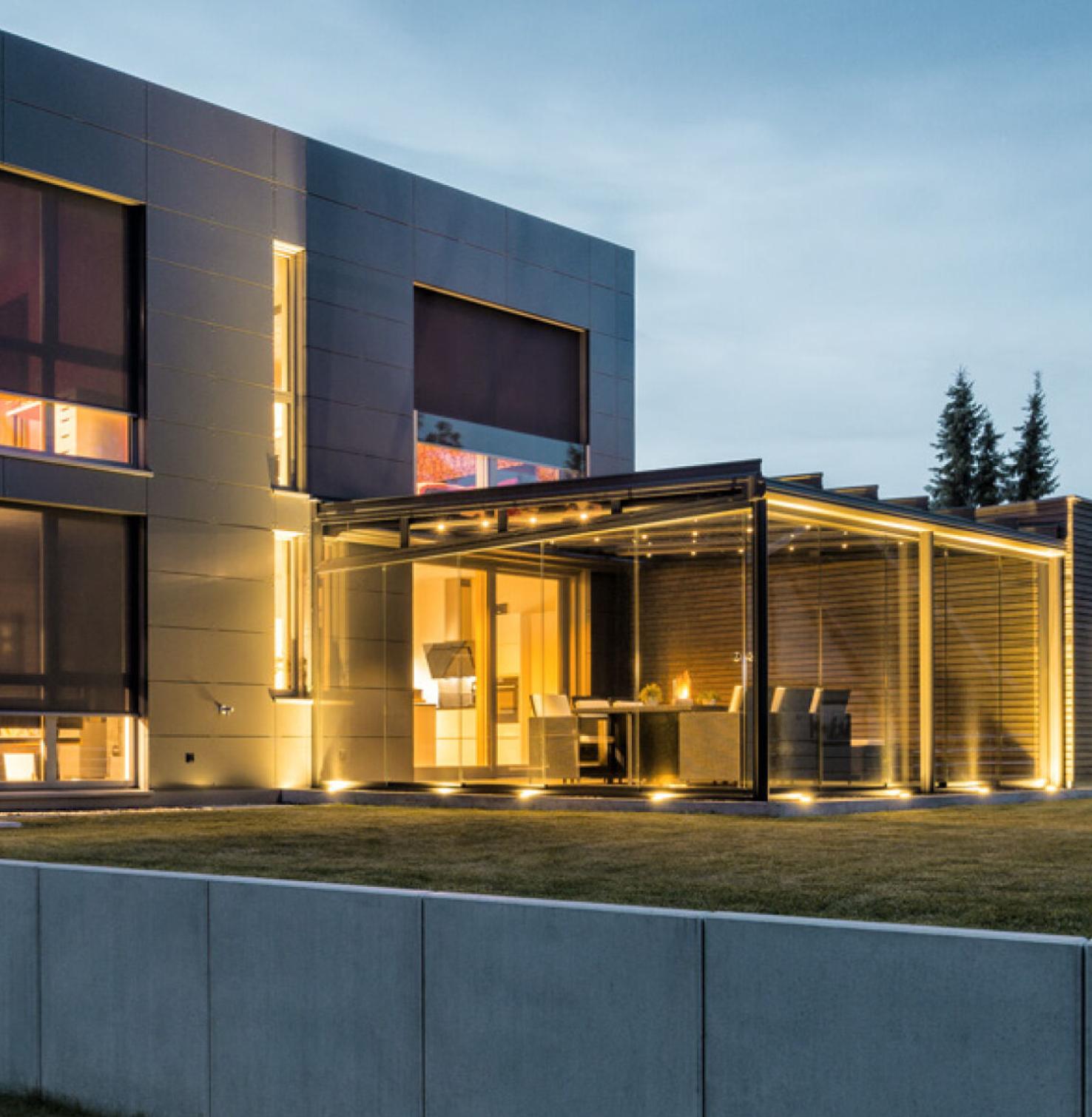 Modernes Haus bei Dämmerung mit Innenbeleuchtung und runtergelassenen Vorbautextilscreens